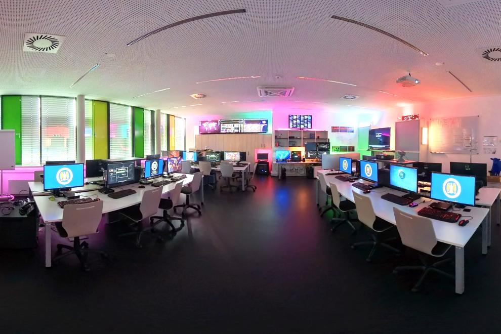 Viele Arbeitsplätze mit Bildschirmen in einem Raum.
